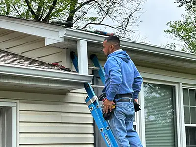 Man on ladder installing new gutters
